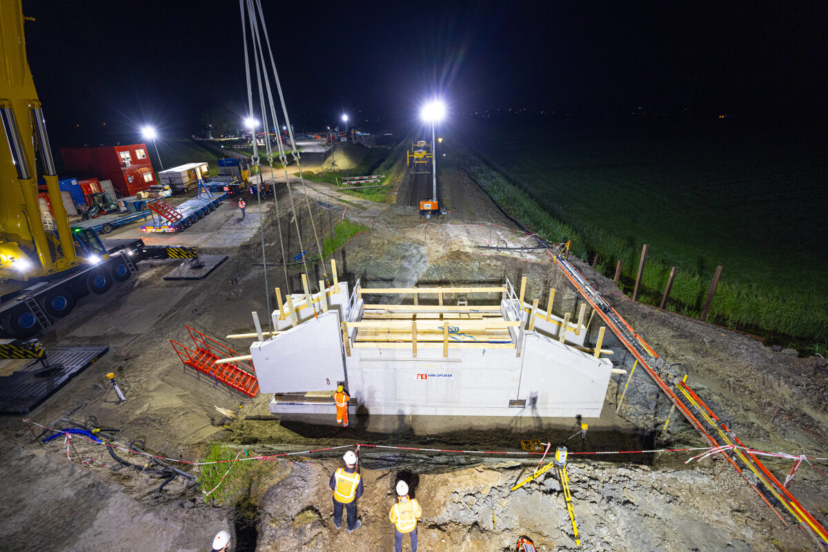 Het inhijsen van prefab tunneldelen bij een onderdoorgang in Deinum
