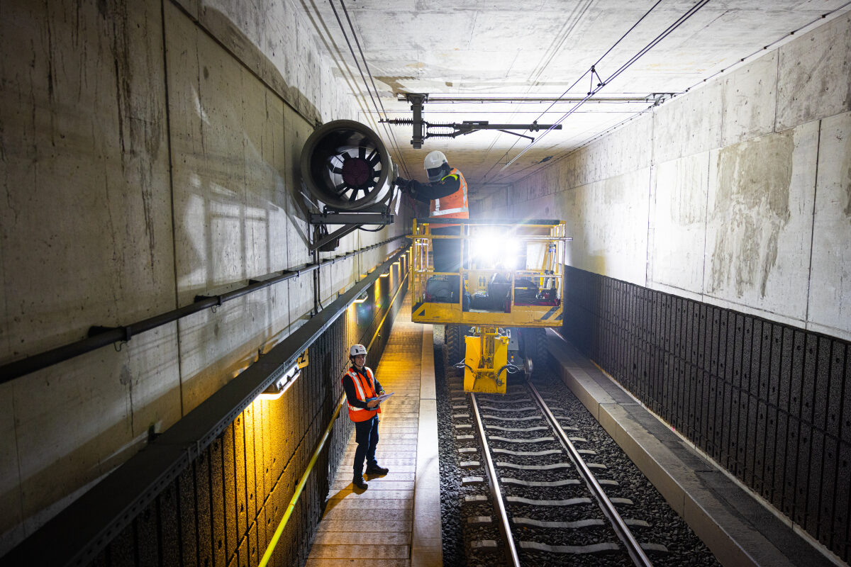 Een medewerker in een hoogwerker voert spanningscontrole uit op een ventilatiesysteem in de spoortunnel van Delft