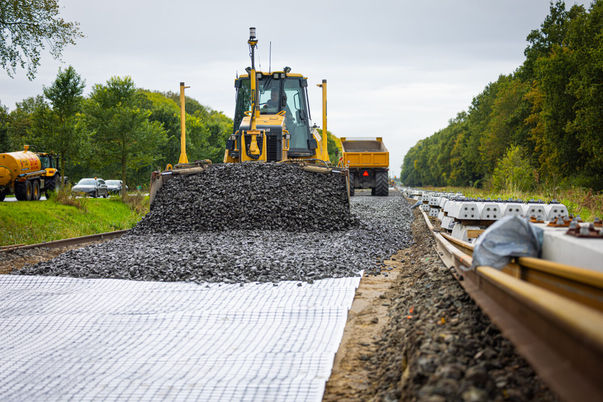 Nieuwe ballast wordt uitgereden over de ballastmatten bij een spoorvernieuwing bij Appingedam