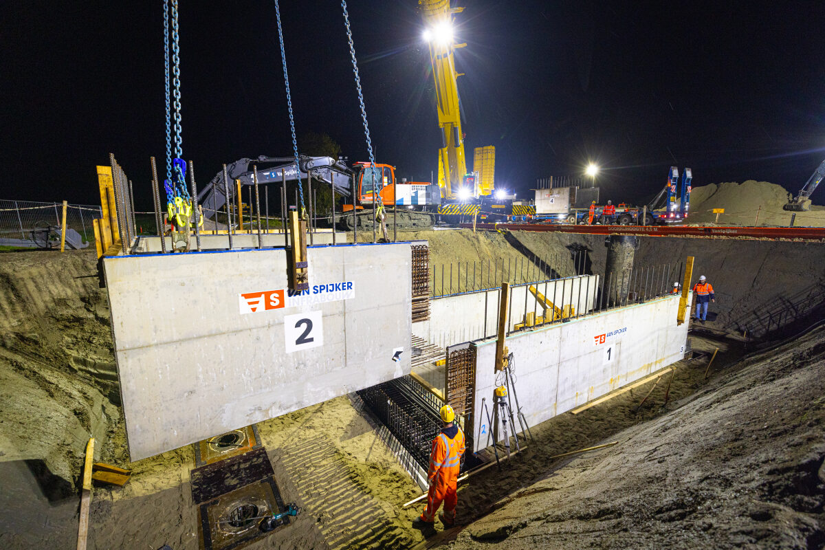 Het inhijsen van prefab tunneldelen voor een onderdoorgang in Eenum