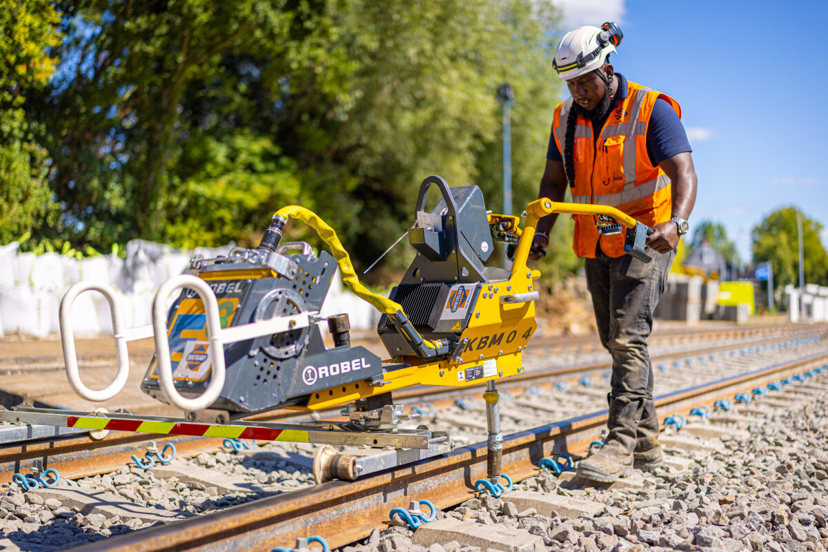 Een spoorwerker is bezig met het vastzetten van bevestigingsmaterialen op het spoor met een elektrische kraagschroefmachine op de Wunderline in Winschoten
