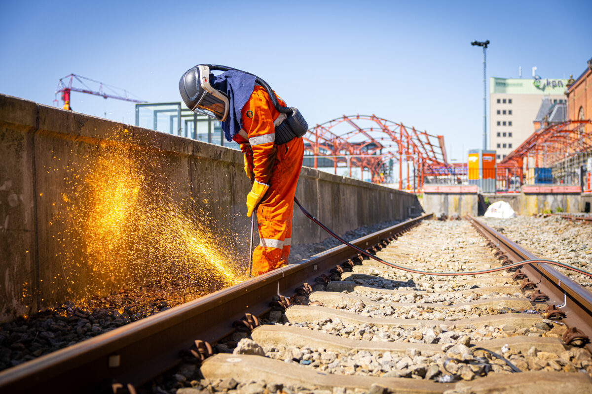 Oude spoorstaven worden doorgesneden met een snijbrander bij de ombouw van het spoor op station Groningen