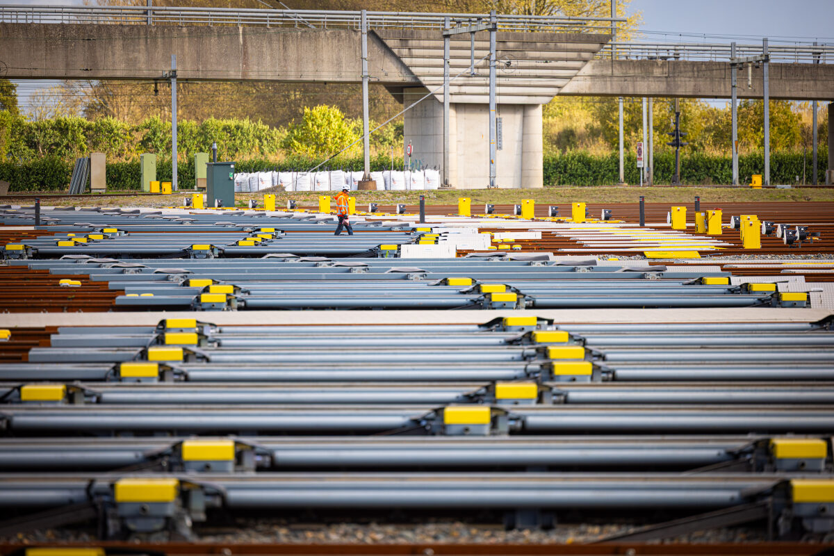 Een medewerker loopt tussen de sporen door op het rangeerterrein Kijfhoek bij Zwijndrecht, met zicht op de railremmen van het heuvelsysteem