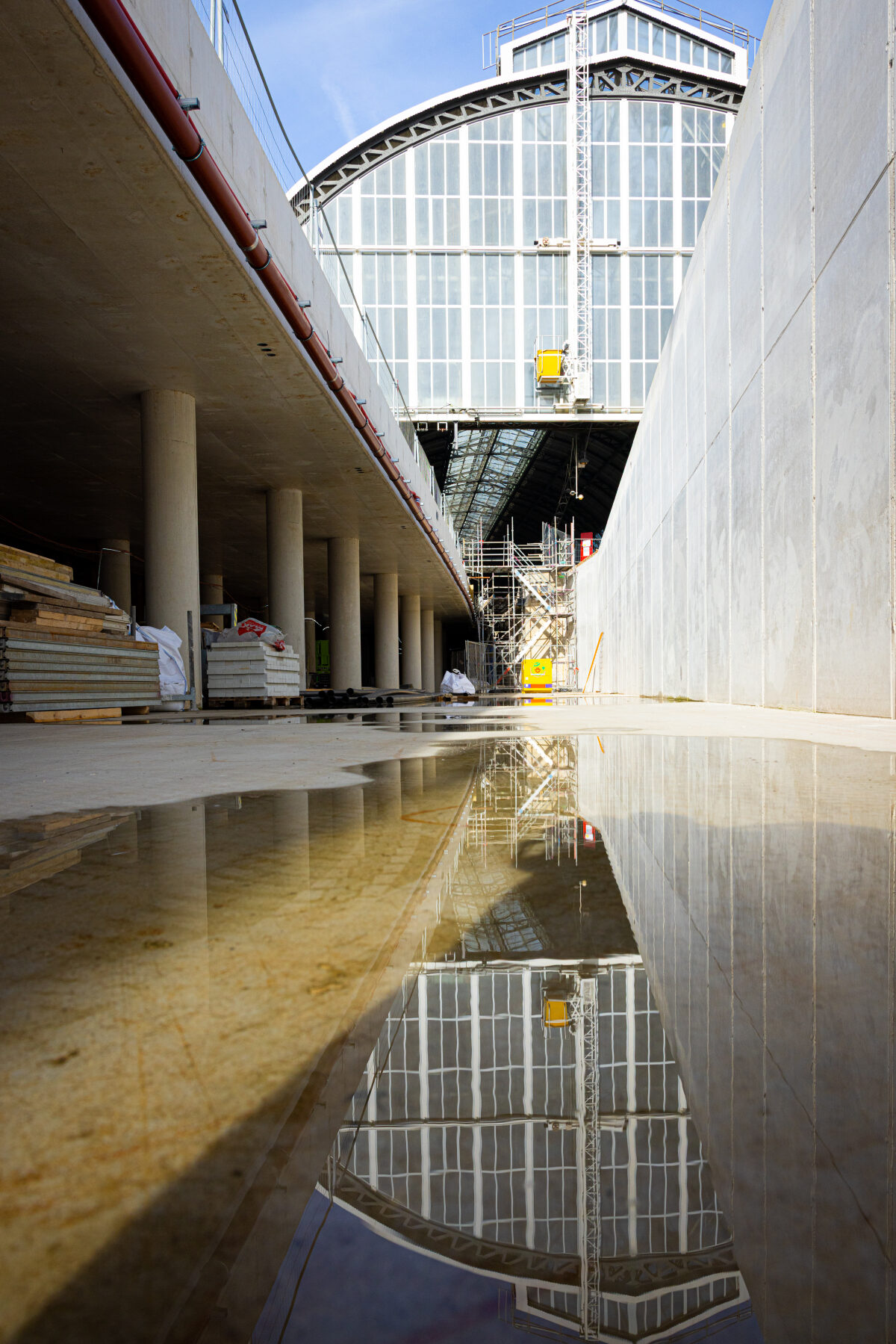De ruimte onder de sporen voor de fietsenstalling met in de reflectie van het water de stationskap van Amsterdam CS
